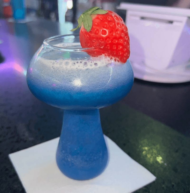 A bright blue kava cocktail garnished with a strawberry